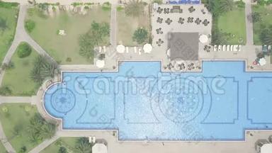 蓝色游泳池，雨伞和绿色草坪在豪华度假酒店从上面的飞行无人机。 高空视野大